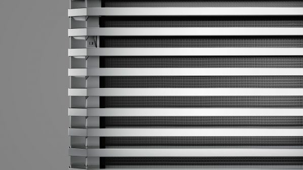 Un primo piano dettagliato di un componente interno di un abbattitore professionale del brand Irinox, che mostra una serie di alette orizzontali in metallo lucido, sovrapposte a una griglia metallica scura. Le alette sono intervallate da barre orizzontali e verticali, creando un design funzionale e robusto. Questa immagine evidenzia la struttura interna del sistema di raffreddamento dell'abbattitore Irinox.