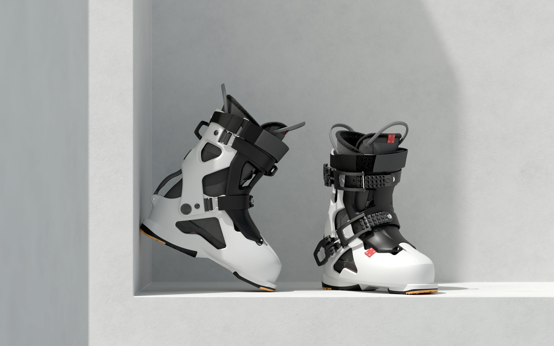 Una coppia di scarponi da sci Dahu della serie Écorce, con il design innovativo che permette la separazione della scarpetta interna dalla scocca esterna. Lo scarpone a sinistra è di colore bianco e nero, con le fibbie e i meccanismi di chiusura aperti, mostrando la sua struttura modulare. Lo scarpone a destra è simile ma con una prevalenza di nero e bianco, con dettagli rossi sulle fibbie. Entrambi gli scarponi sono posizionati su una superficie bianca con ombre definite, mettendo in risalto la loro estetica moderna e la tecnologia di costruzione, tipica dei prodotti Dahu.