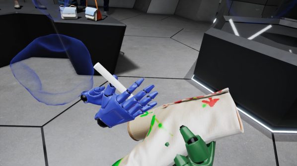 Screenshot da un ambiente di realtà virtuale o 3D che mostra una mano robotica blu che tiene un oggetto cilindrico bianco. Sulla superficie beige o bianca in primo piano, che sembra parte di un braccio o di un oggetto, sono visibili macchie di vernice verde e rossa. Sullo sfondo, si intravedono forme blu traslucide e un ambiente virtuale con pareti e pavimento a griglia esagonale. L'immagine comunica un'interazione o una modifica in corso in un contesto di design review virtuale o prototipazione.
