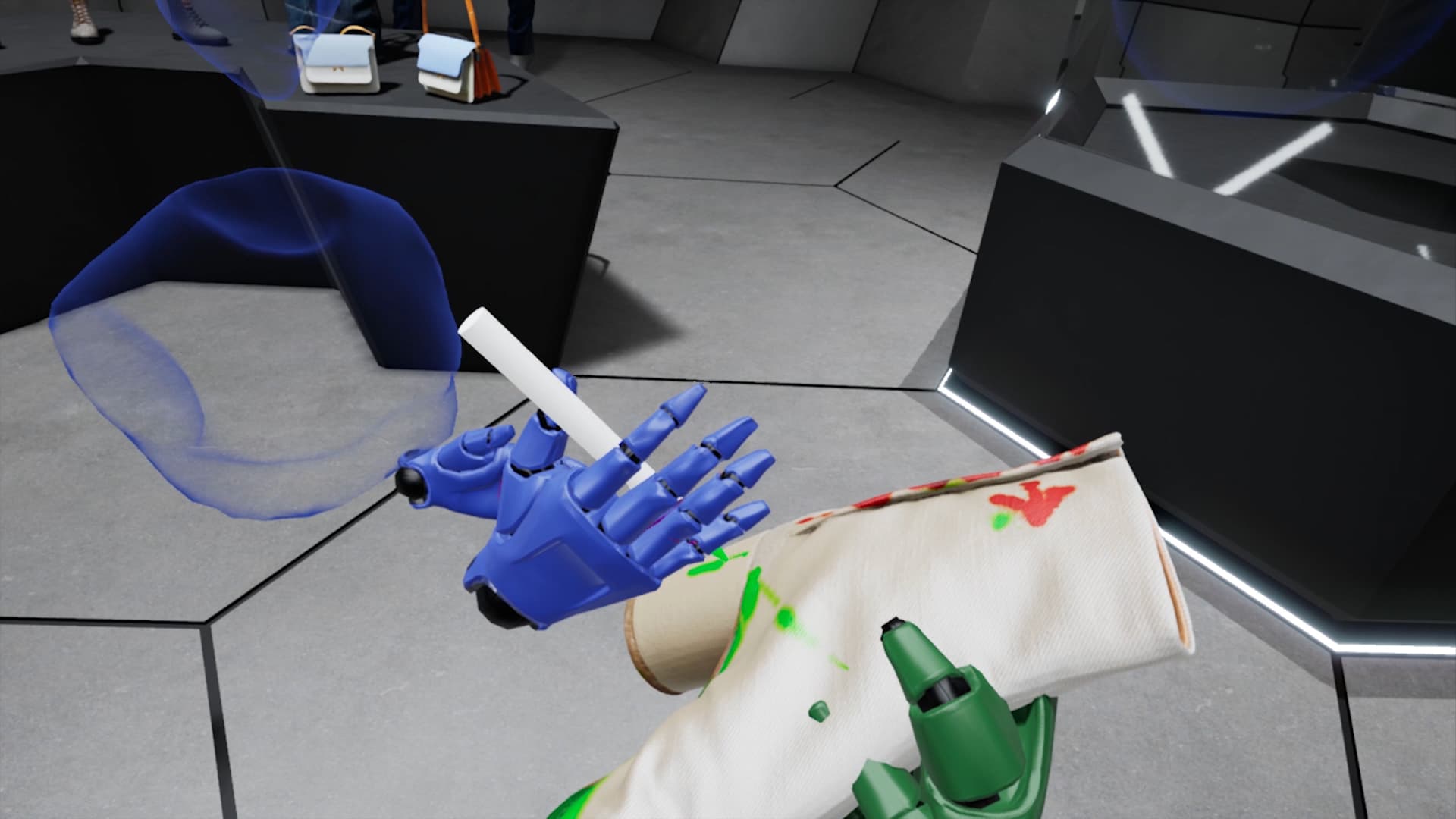 Screenshot da un ambiente di realtà virtuale o 3D che mostra una mano robotica blu che tiene un oggetto cilindrico bianco. Sulla superficie beige o bianca in primo piano, che sembra parte di un braccio o di un oggetto, sono visibili macchie di vernice verde e rossa. Sullo sfondo, si intravedono forme blu traslucide e un ambiente virtuale con pareti e pavimento a griglia esagonale. L'immagine comunica un'interazione o una modifica in corso in un contesto di design review virtuale o prototipazione.