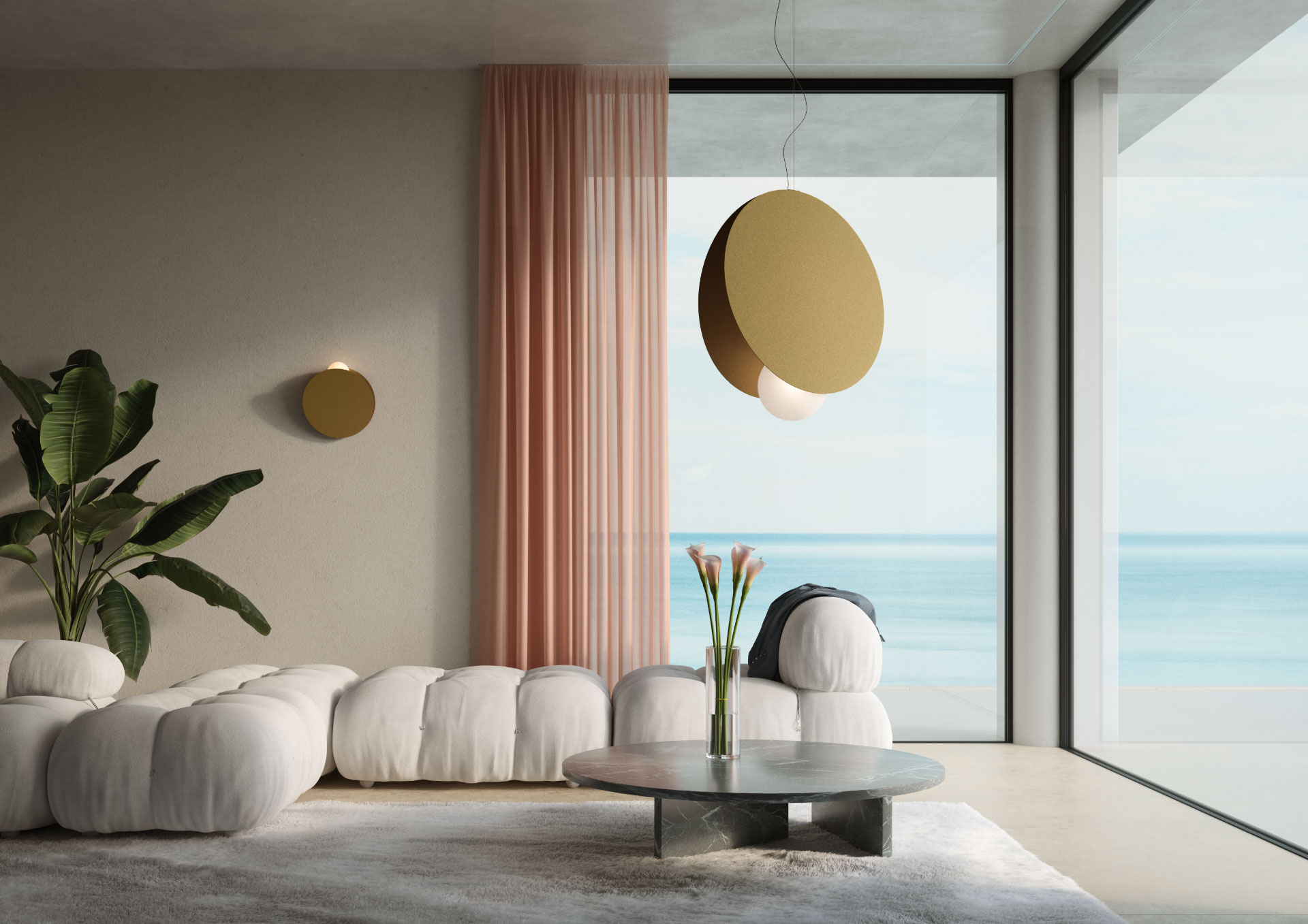 Un elegante salotto moderno con un divano modulare bianco imbottito e un tavolino da caffè rotondo in marmo grigio. Sul tavolino, un vaso con fiori rosa. Una grande lampada a sospensione di colore dorato con un globo luminoso bianco pende dal soffitto. Le pareti sono chiare e una tenda rosa voluminosa è drappeggiata a sinistra di un'ampia finestra che si affaccia sul mare.