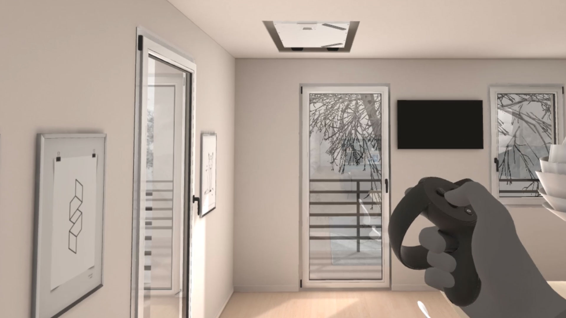 Un rendering 3D di un interno moderno, probabilmente un soggiorno o uno studio, con pareti chiare e un pavimento in legno. A sinistra, un quadro incorniciato appeso a una parete. Al centro, una porta-finestra che si affaccia su un paesaggio invernale, e sulla parete un televisore nero montato. In primo piano a destra, una mano virtuale con un controller VR grigio interagisce con l'ambiente. In alto, una botola sul soffitto.